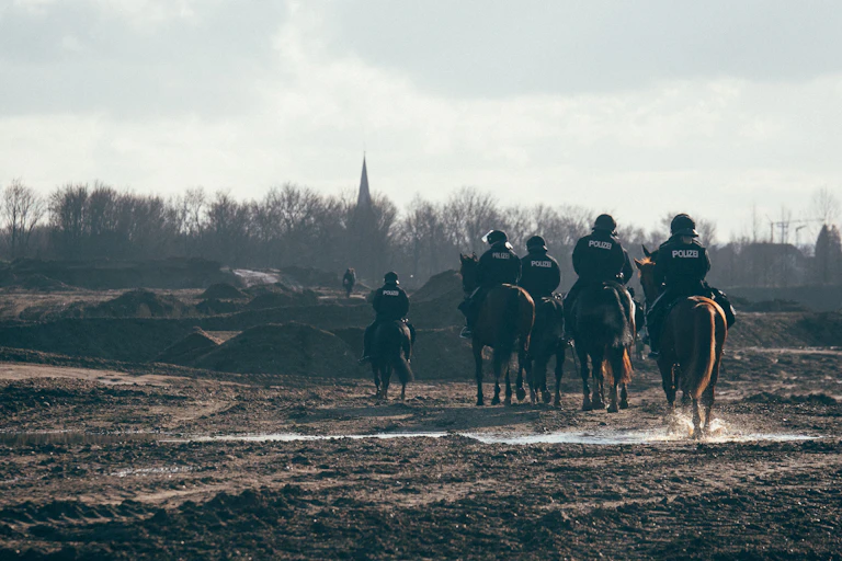 Police horses walk across bare ground