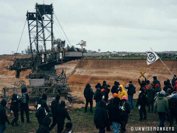 Protesters by large hole with industrial machinery