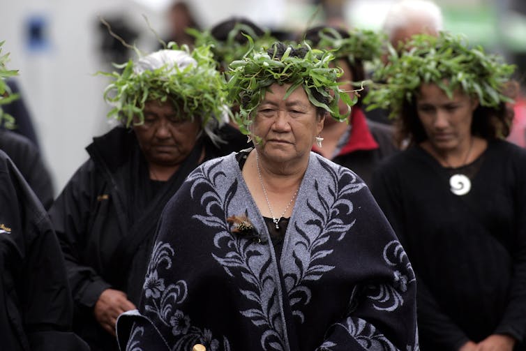 Mourners with wreaths on their heads.