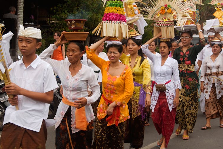 People walking along road in colourful clothing.