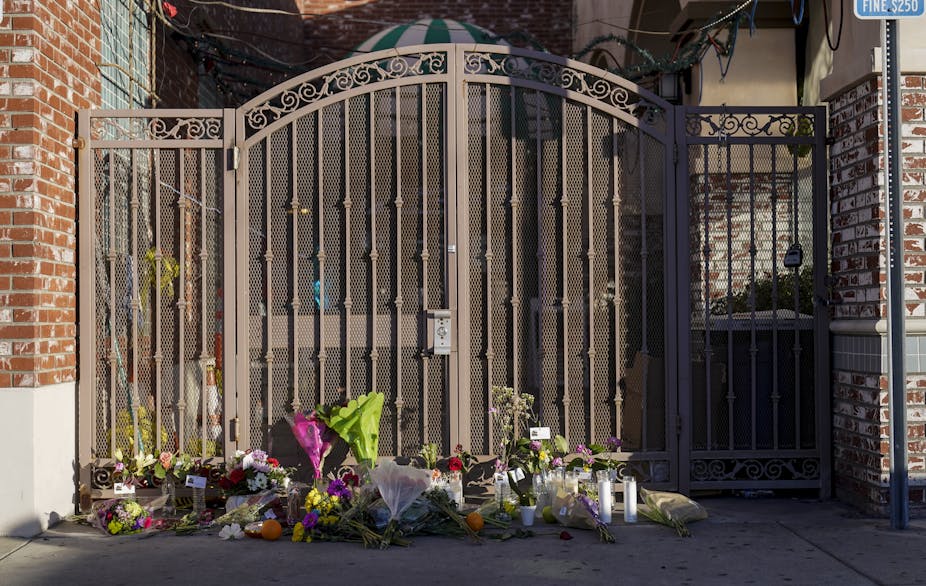 An array of flower bouquets lying at the foot of the entrance gate to the dance studio where the Jan. 21, 2023, mass shooting occurred.