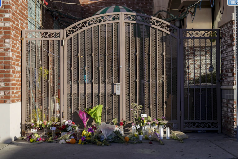 An array of flower bouquets lying at the foot of the entrance gate to the dance studio where the Jan. 21, 2023, mass shooting occurred.