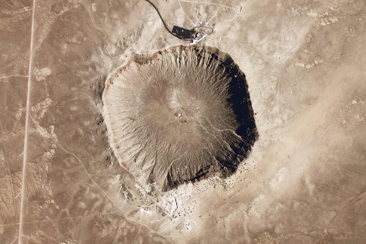 A light brown landscape viewed directly from above, with a round pockmark in the middle