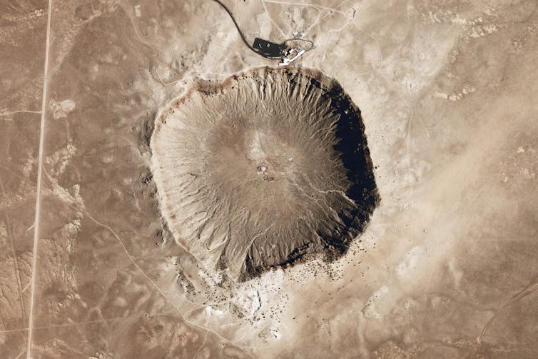 Un paisaje marrón claro visto directamente desde arriba, con un agujero circular en el centro