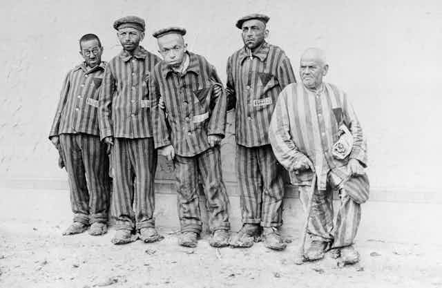 Five men in prison striped pyjamas, photographed in black and white. Some are visibly handicapped.