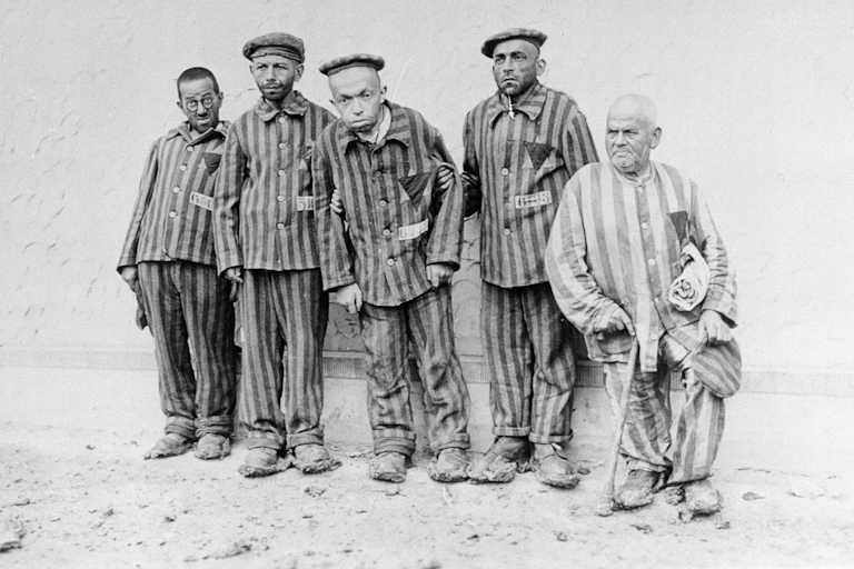 Five men in prison striped pyjamas, photographed in black and white. Some are visibly handicapped.