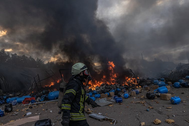 Man walks past burning pile of refuse
