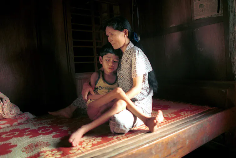 woman comforts son on bed