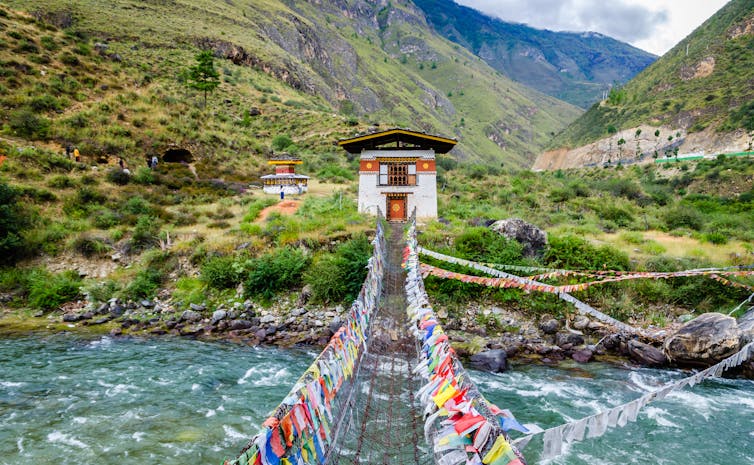 Bridge covered in flags with hills in the background.