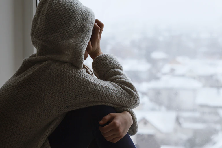 Child wearing hood looking out of window