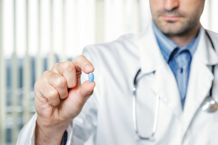A doctor holding a blue pill.