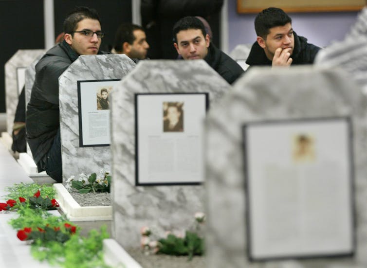 Students seen sitting with sombre faces next to cutouts made to look like gravestones.