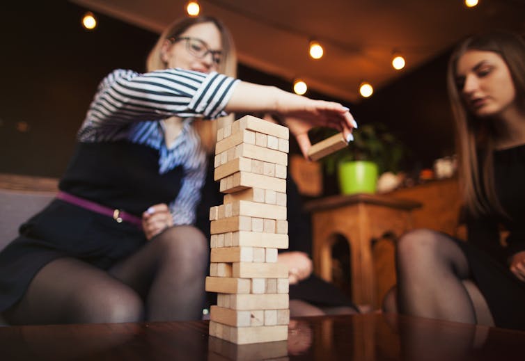 Two young women playing Jenga in a public cafe