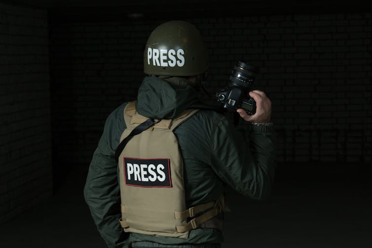a person wearing a flak jacket and helmet with the words PRESS printed on them