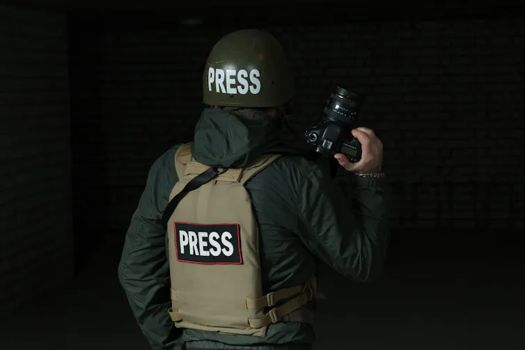 a person wearing a flak jacket and helmet with the words PRESS printed on them