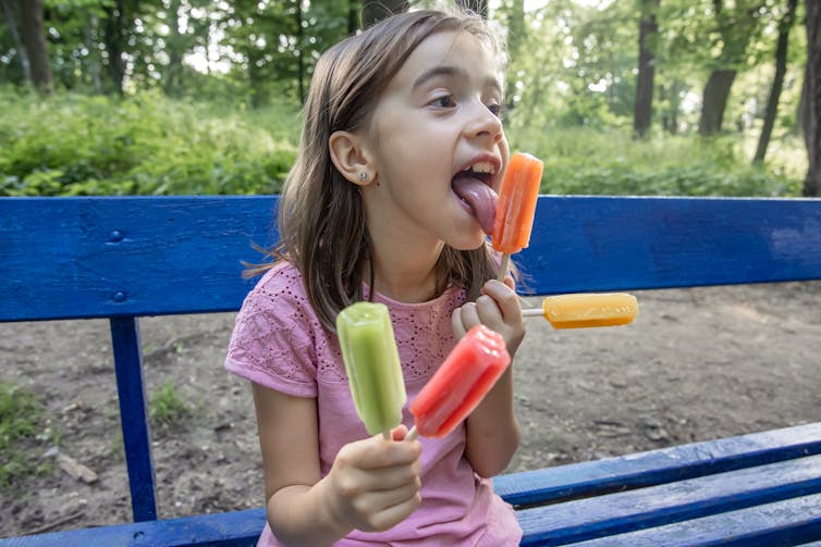 girl eating several colourful icypoles