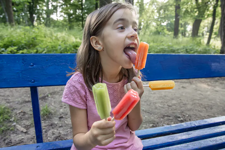 girl eating several colourful icypoles