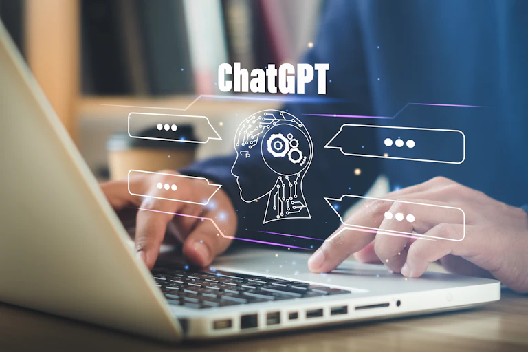 a graphic of a silhouetted head and the text CHATGPT float above a laptop's keyboard