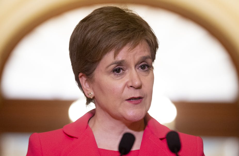 Face and shoulders of Nicola Sturgeon wearing a red jacket.
