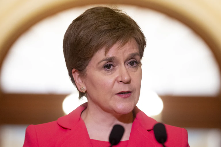 Face and shoulders of Nicola Sturgeon wearing a red jacket.