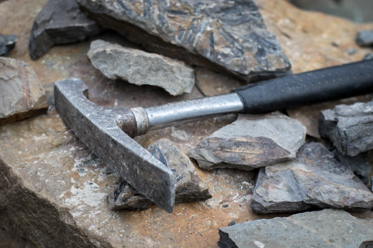 Hammer tool and excavated fossils imprinted on rocks.