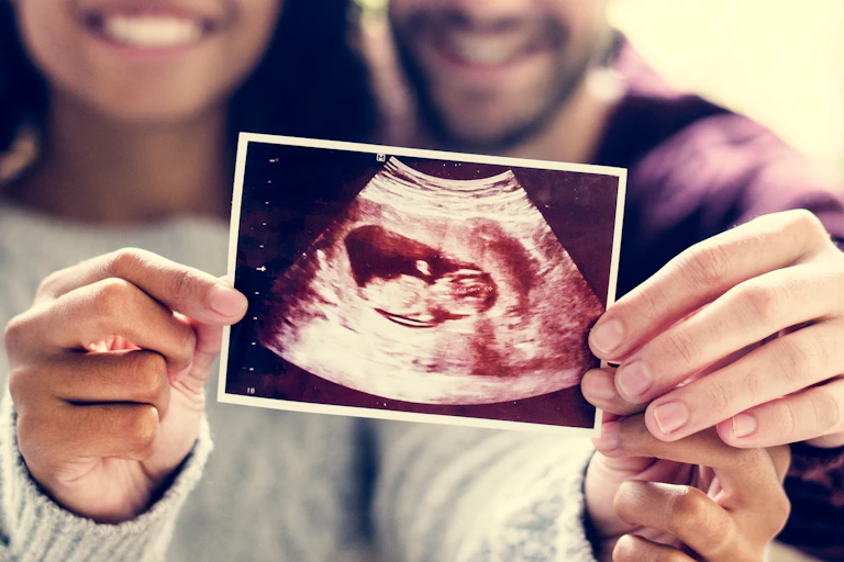 Parents holding up a baby scan