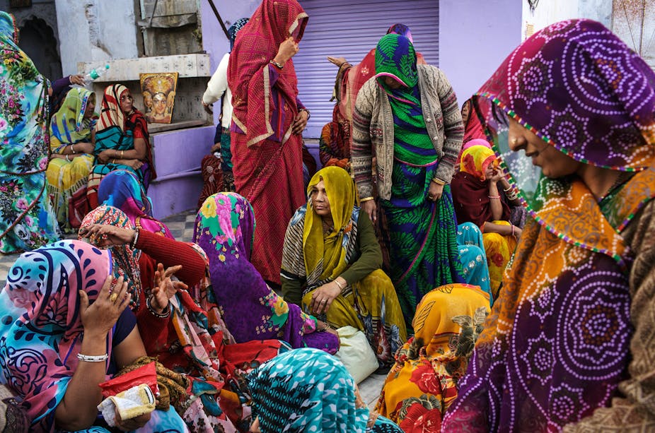 A group of colourfully dressed women mourning a death in India.
