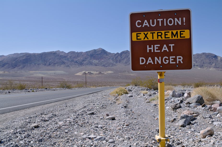 A sign planted in a gravel road reads Caution! Extreme Heat Danger; the words are white on brown, and "Extreme" is highlighted in yellow