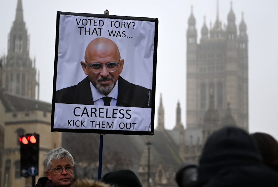 A person holds a placard showing a photo of Conservative Party Chairman Nadhim Zahawi, during a protest outside the parliament building in London, Britain, 25 January 2023.