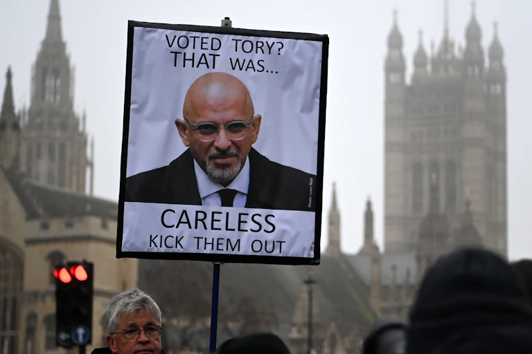 A person holds a placard showing a photo of Conservative Party Chairman Nadhim Zahawi, during a protest outside the parliament building in London, Britain, 25 January 2023.