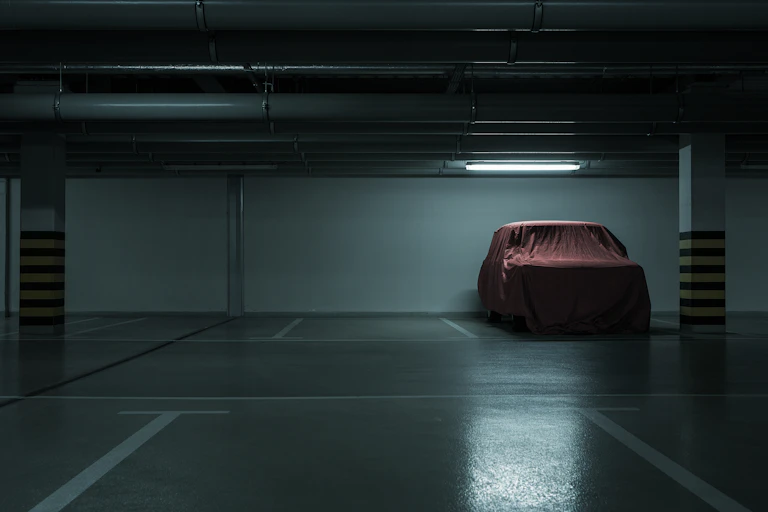 Car with a red cover sits in an otherwise empty parking garage.