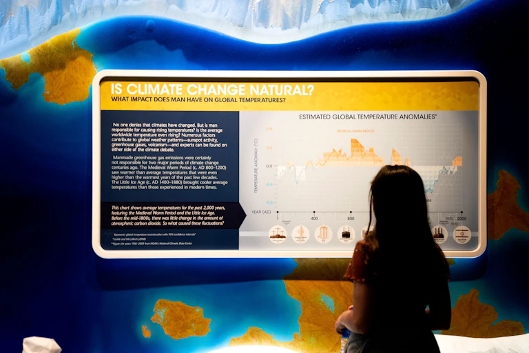 A child standing in front of a large display which has a question: Is climate change natural?