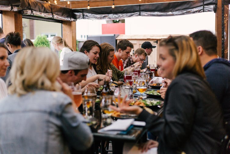 A large group of people around a table with food and drinks