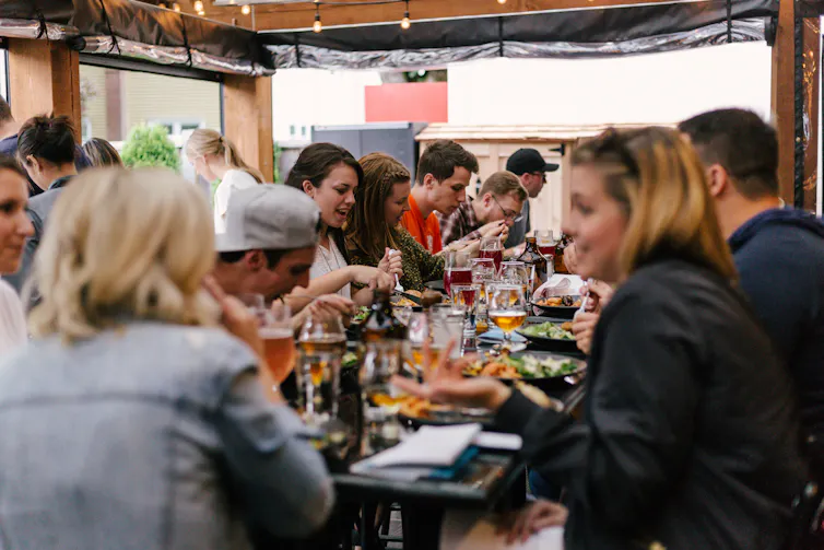 A large group of people around a table with food and drinks