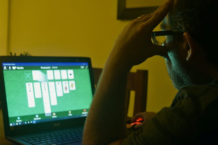 A man playing solitaire on a computer screen