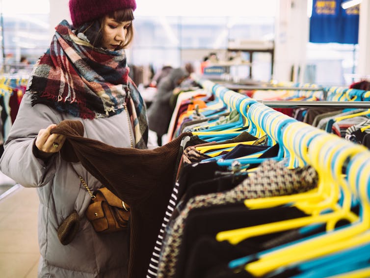 Une jeune femme dans un magasin de vêtements de seconde main