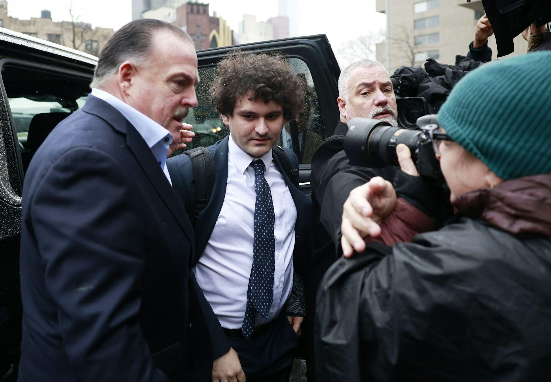 Sam Bankman-Fried in a suit steps out of a car for his court appearance