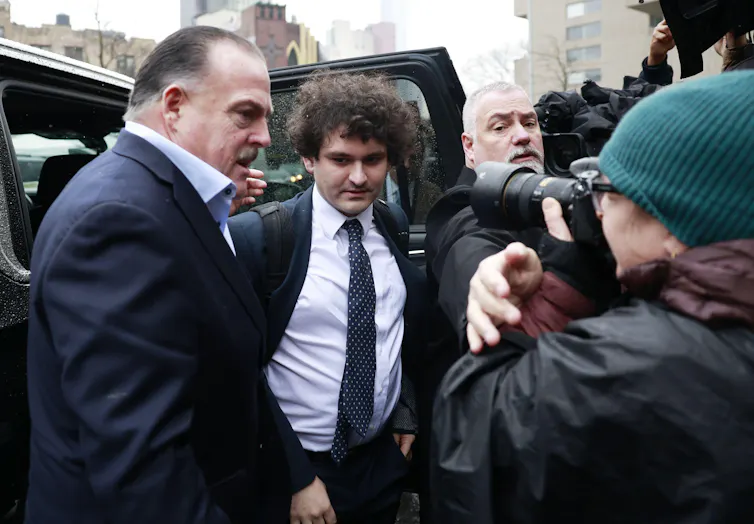 Sam Bankman-Fried in a suit steps out of a car for his court appearance