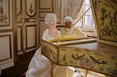 Une femme joue du piano sous le regard d’un homme noir