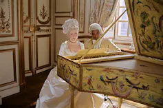 Une femme joue du piano sous le regard d’un homme noir