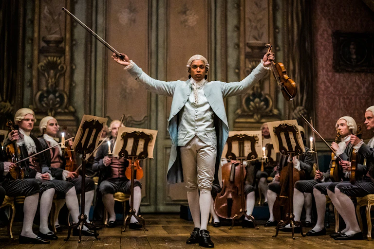 Un hombre negro alza su violín y su arco entre violinistas blancos en una escena de una película de época.