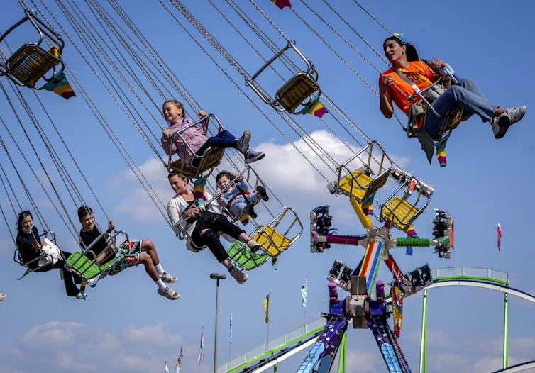 Children smile and laugh as they ride an amusement park ride.