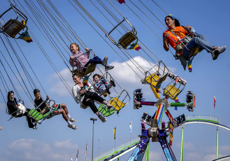 Children smile and laugh as they ride an amusement park ride.