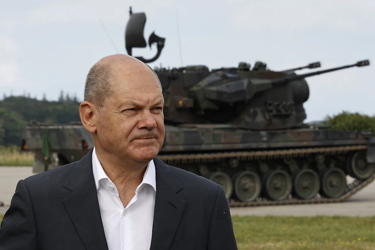 A man stands in front of a tank.