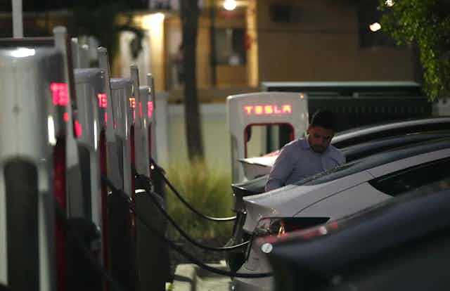 A driver charges his car at a Tesla Supercharger station in Miami. 