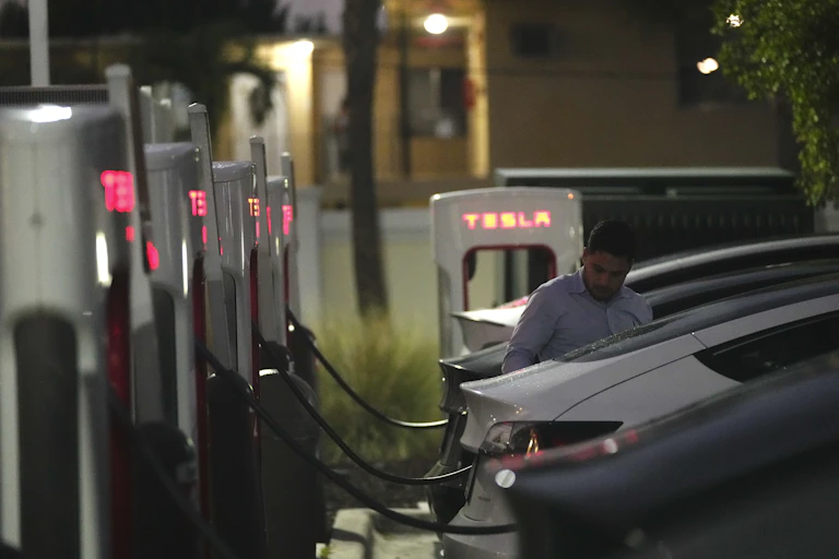 A driver charges his car at a Tesla Supercharger station in Miami.