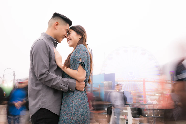 An East Asian man and woman hold each other while smiling.