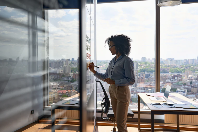 A young woman writing on a whiteboard in an office