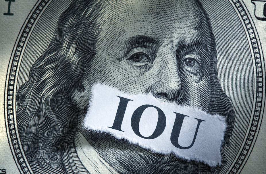 Closeup of Ben franklin's face on a $100 bill with letters IOU covering his mouth