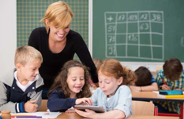 Teacher helping three primary students. 